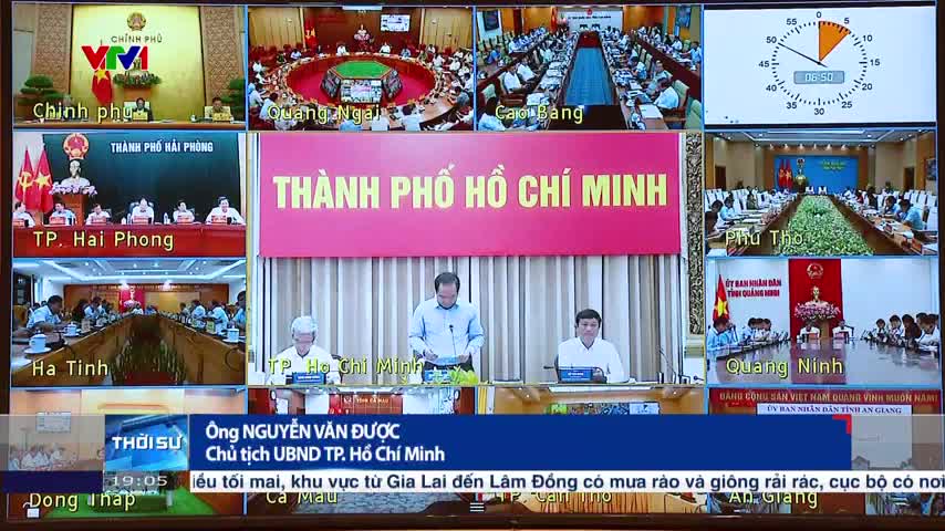 On the screen, a man in a light blue shirt speaks from a podium, while a clock ticks in the corner. Various other screens show meetings taking place across different regions of Vietnam, all broadcast on VTV1.
