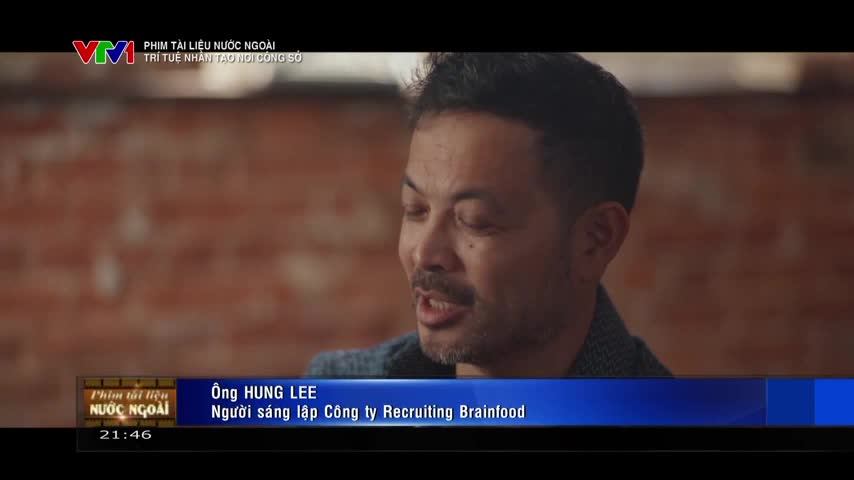 A man with dark hair and a gray jacket is speaking, his mouth moving as he gestures. Below him, a VTV1 graphic identifies him as Ông Hung Lee, founder of Recruiting Brainfood.
