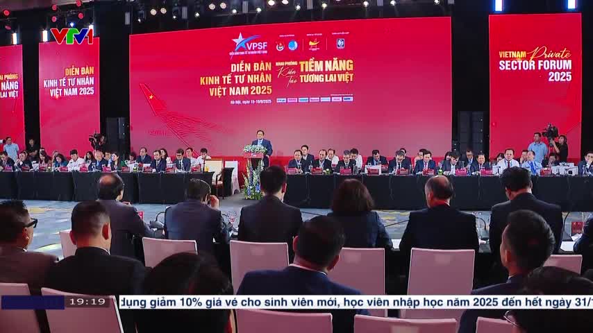 A man in a suit speaks from a podium, addressing a room full of seated people. Behind him, the words "Vietnam Private Sector Forum 2025" are displayed on a large red screen, likely broadcast on VTV1.
