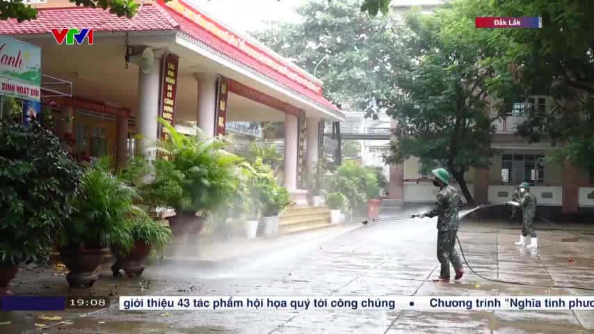Two soldiers in uniform are spraying down the courtyard with high-pressure hoses, creating a mist that obscures the building's facade. The scene is being broadcast on VTV1, with a banner noting the location as Đắk Lắk.
