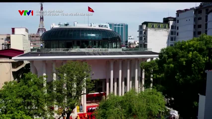 A lone figure stands on the roof of a modern building in Hanoi, its glass dome reflecting the sky. The VTV1 logo is visible in the corner, indicating a broadcast from Vietnam.